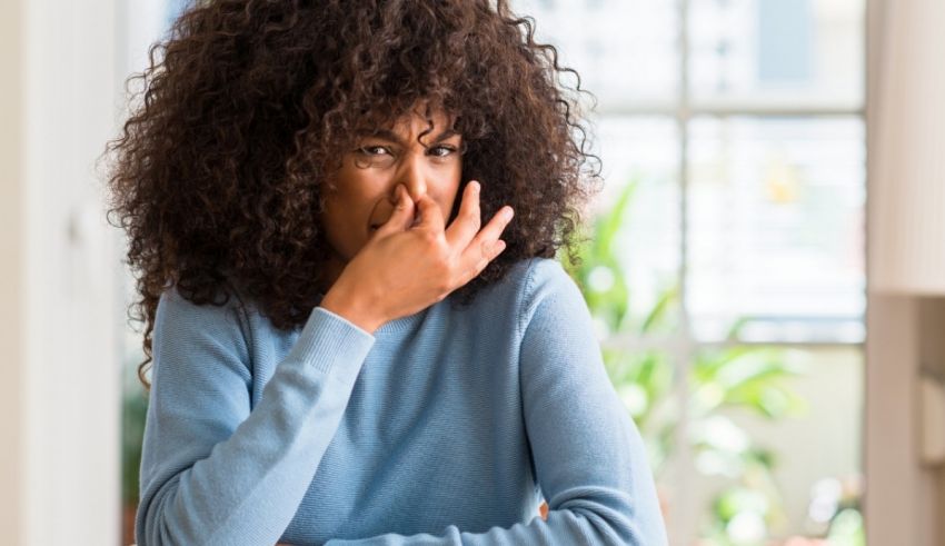 A woman with curly hair sitting at a table with her hand on her face.