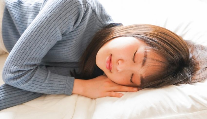 A young asian woman sleeping on a white bed.