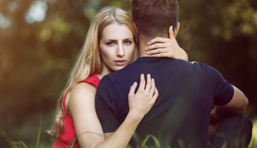 A man and woman hugging in the grass.