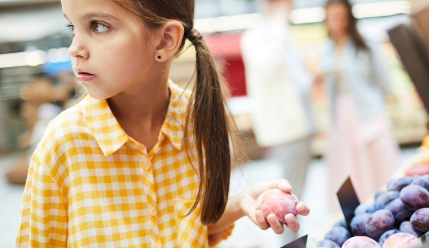 A young girl looking at fruit in a grocery store.