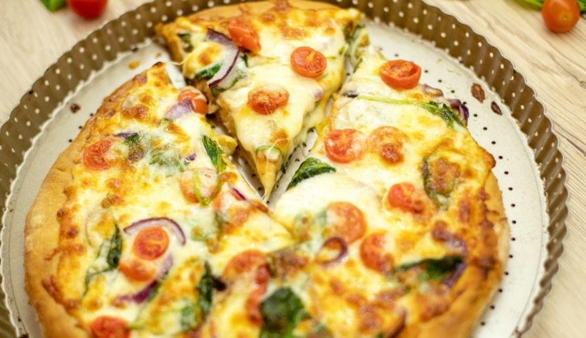 A pizza with tomatoes and spinach on a plate.