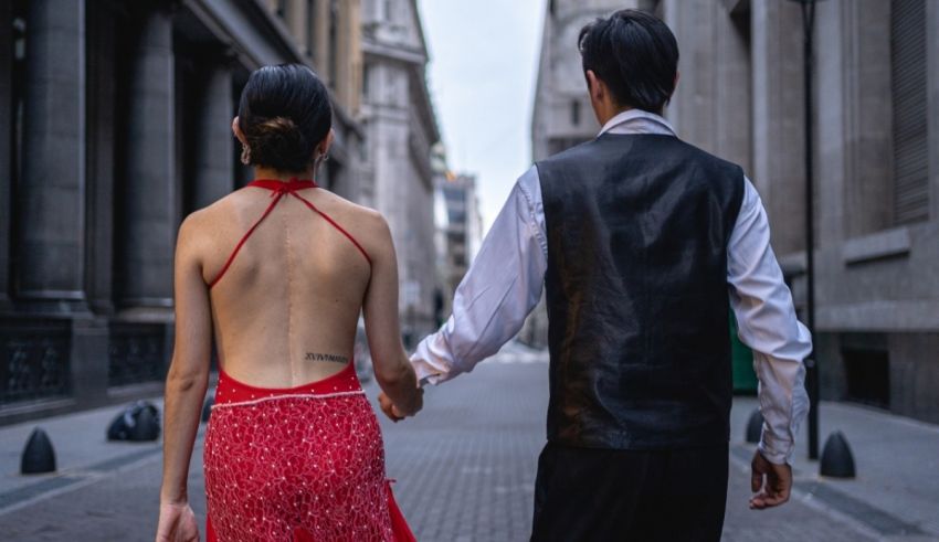 A man and woman walking down a street in a red dress.