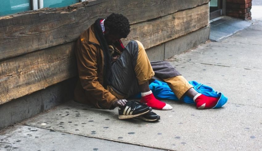 A homeless man sleeping on a sidewalk.