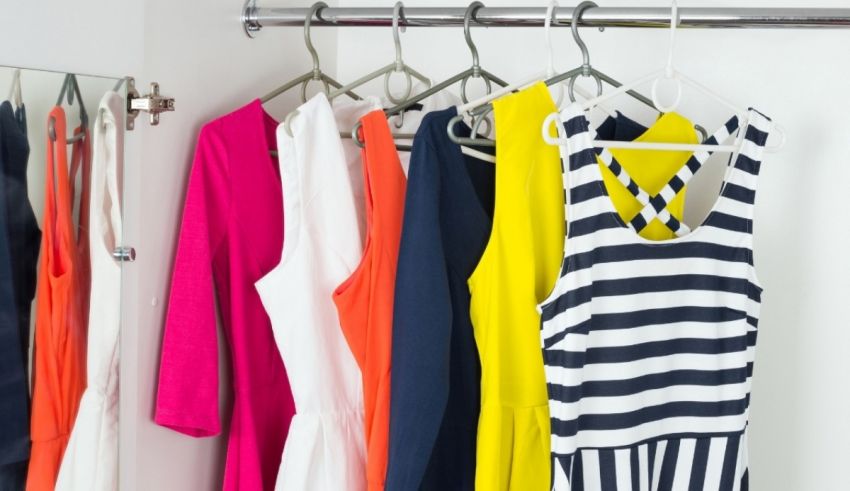 Colorful clothes hanging on a rack in a closet.