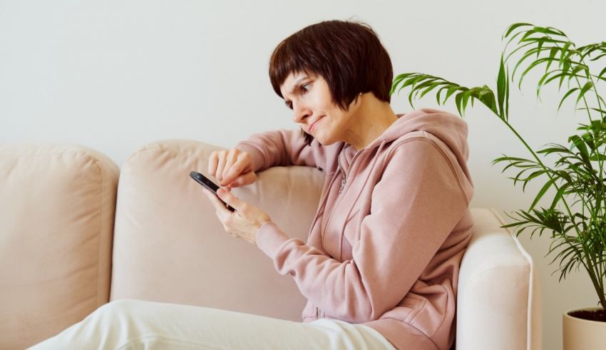 A woman sitting on a couch looking at her phone.