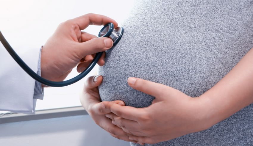 A pregnant woman is being examined by a doctor with a stethoscope.