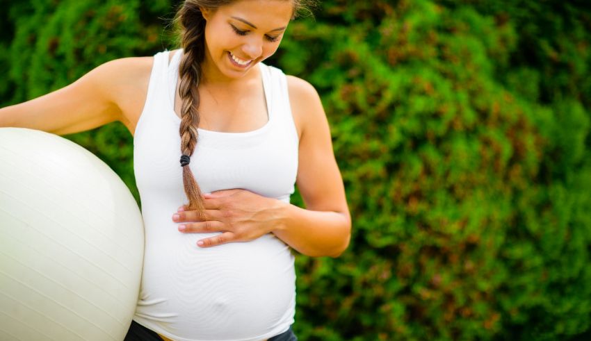 A pregnant woman holding an exercise ball.