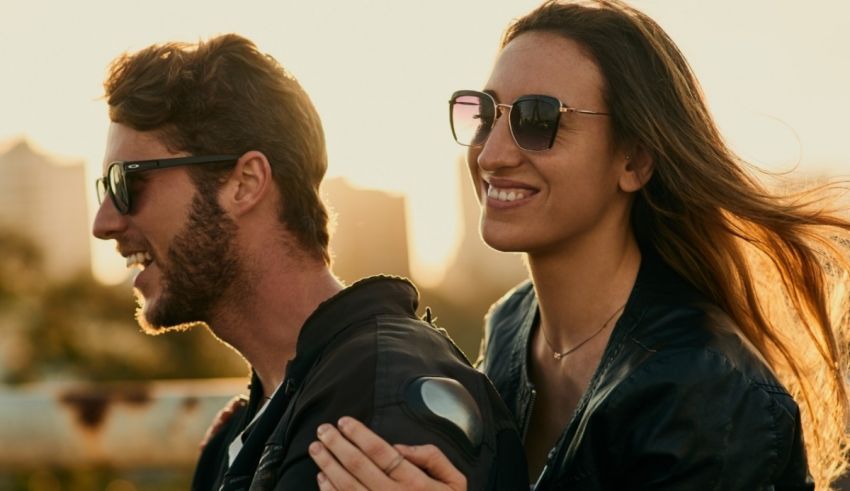 A man and woman are wearing sunglasses and smiling at each other.