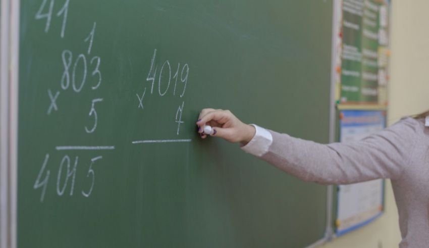 A teacher writing numbers on a blackboard.