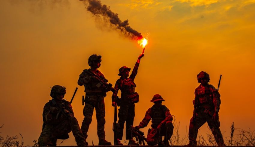 A group of soldiers holding a torch at sunset.