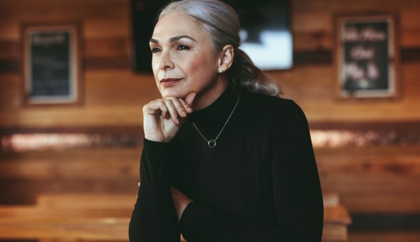 A woman sitting in a restaurant with her hand on her chin.