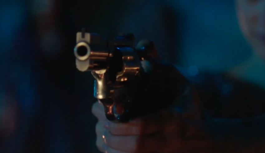 A woman is holding a gun in the dark.