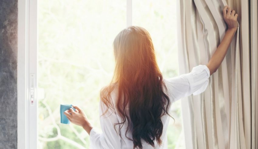 A woman looking out the window with a cup of coffee.