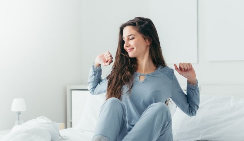 A young woman is sitting on a bed in her pajamas.