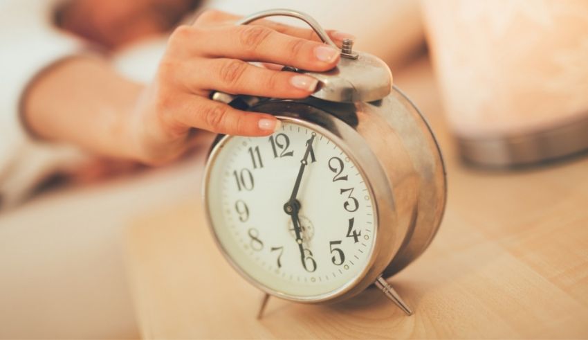 A woman's hand is holding an alarm clock.