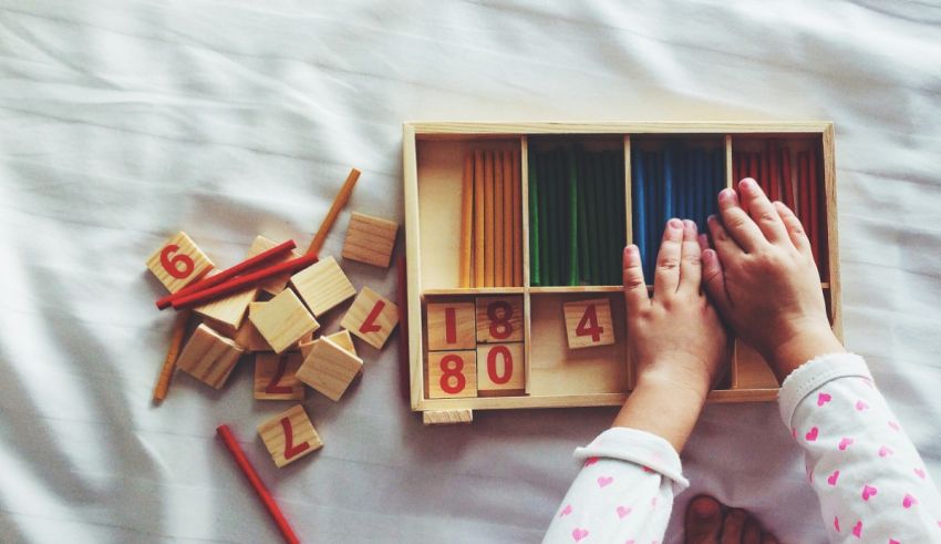 A child is playing with wooden blocks on a bed.