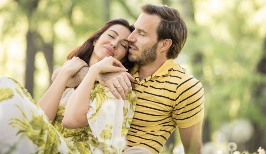 A man and woman hugging in a park.