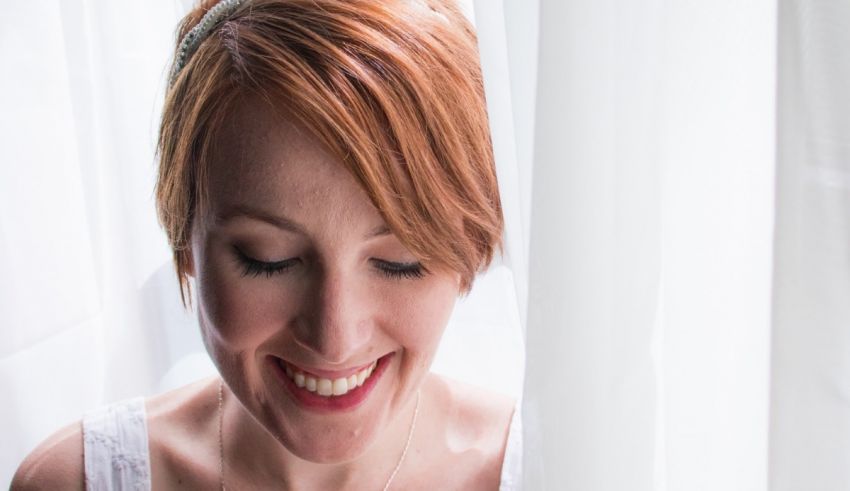 A bride smiling in front of a curtain.