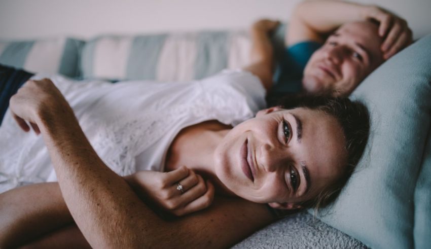 A man and woman laying on a couch and smiling.