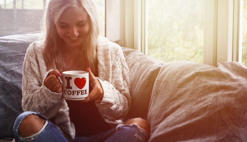 A woman sitting on a couch holding a coffee mug.