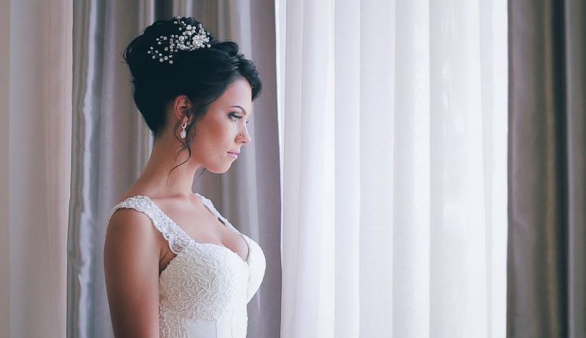 A bride in a wedding dress looking out of a window.