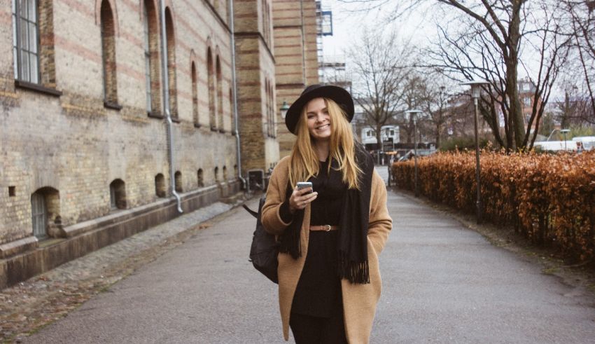 A woman walking down a street holding her cell phone.