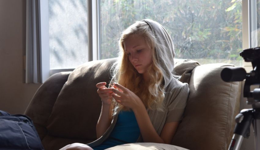 A girl in a hoodie sitting on a couch.