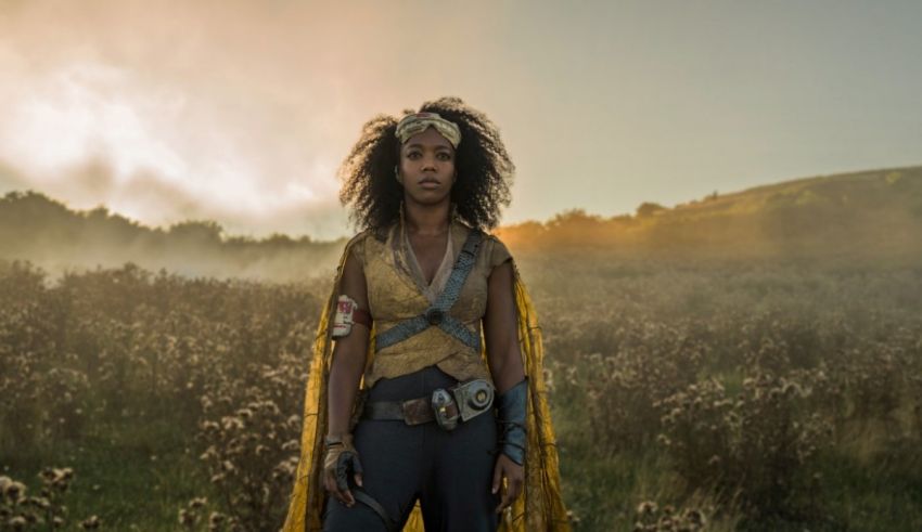 A woman in a yellow cape standing in a field.