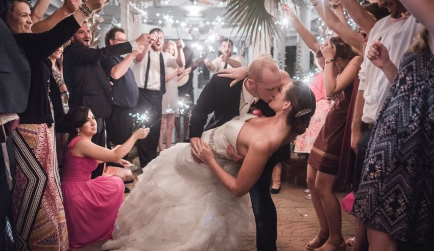 A bride and groom kiss in front of a crowd of sparklers.