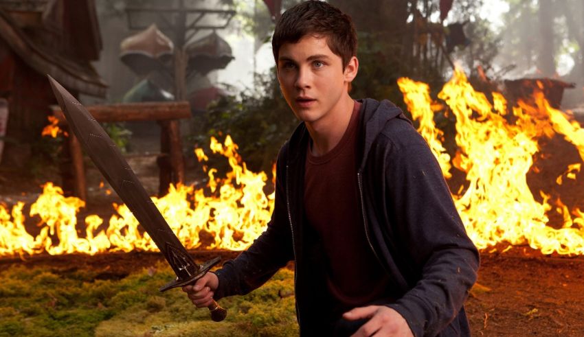 A young man holding a sword in front of a fire.