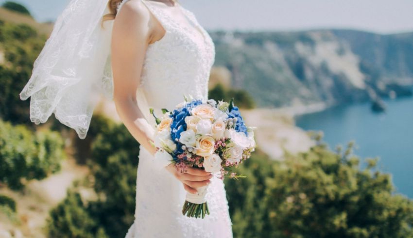 A bride with a bouquet of flowers standing on a cliff overlooking the sea.