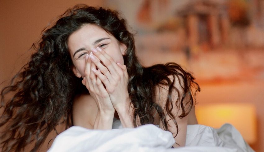 A woman is laying in bed with her face covered.