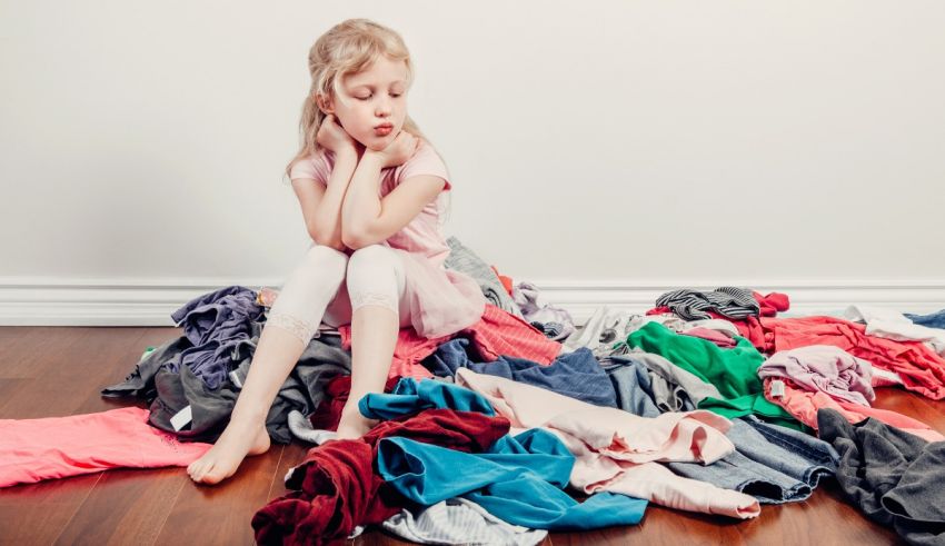 A little girl sitting in front of a pile of clothes.