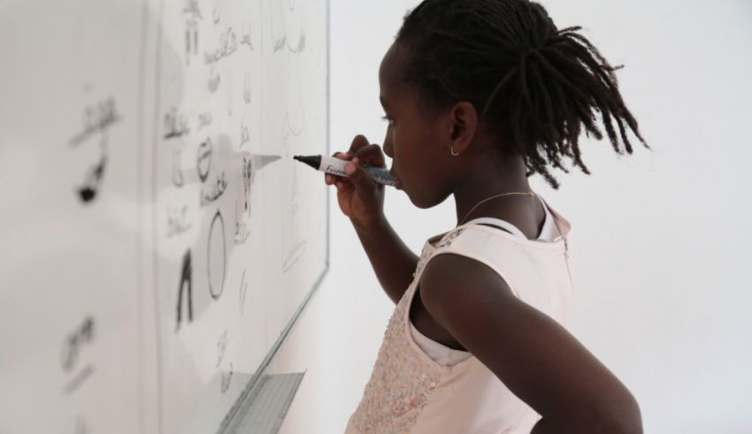 A young girl writing on a whiteboard.