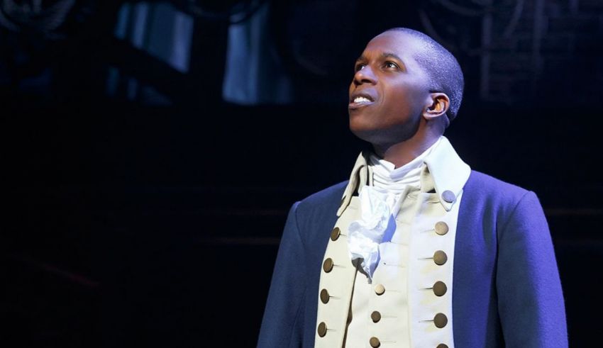 A man in a period costume is standing in front of a stage.