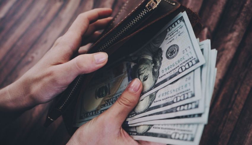 A woman's hand holding a wallet full of money.