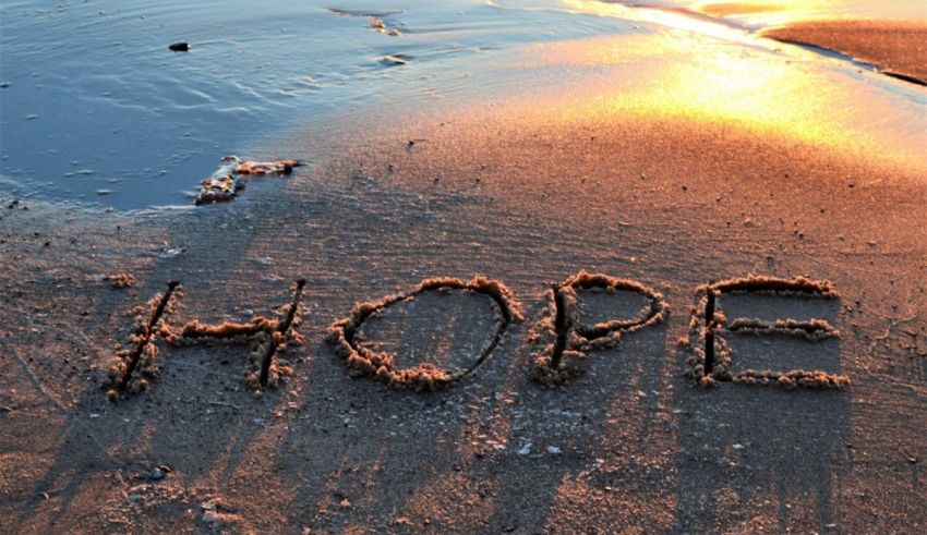 The word hope written in the sand at sunset.