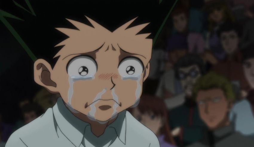 A boy is crying in front of a crowd of people.