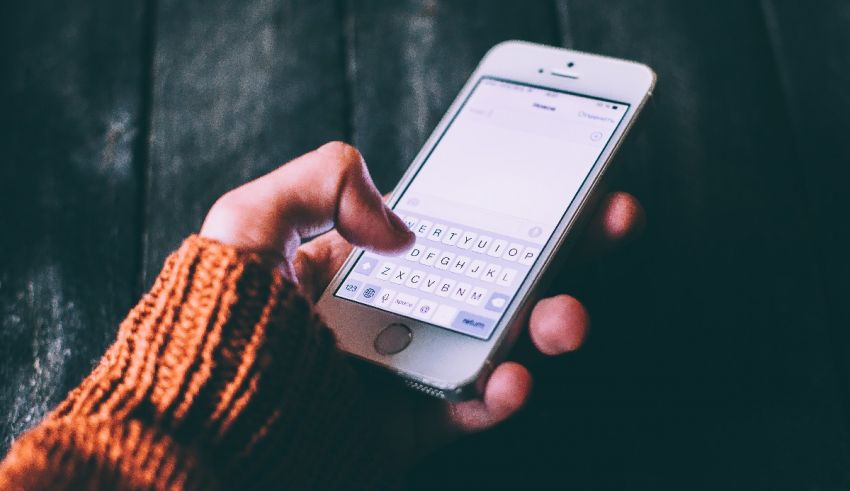 A person holding a cell phone and typing on it.