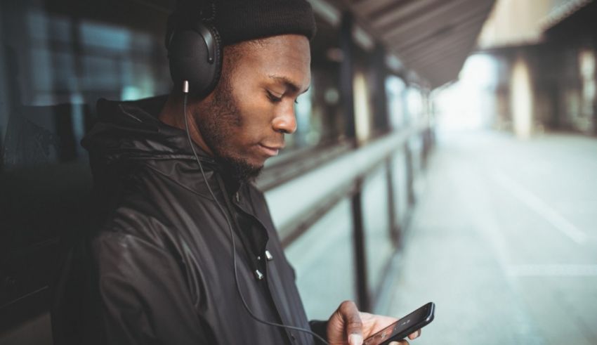 A man wearing a jacket and headphones is looking at his phone.