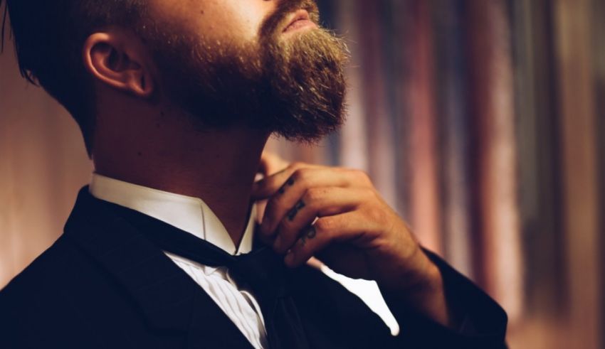 A man with a beard adjusting his tie.