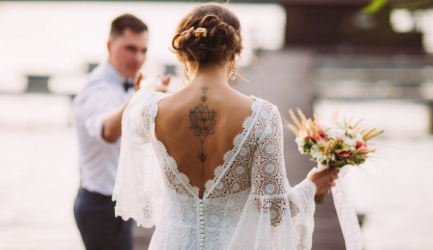 A bride and groom walking down a dock with tattoos on their backs.