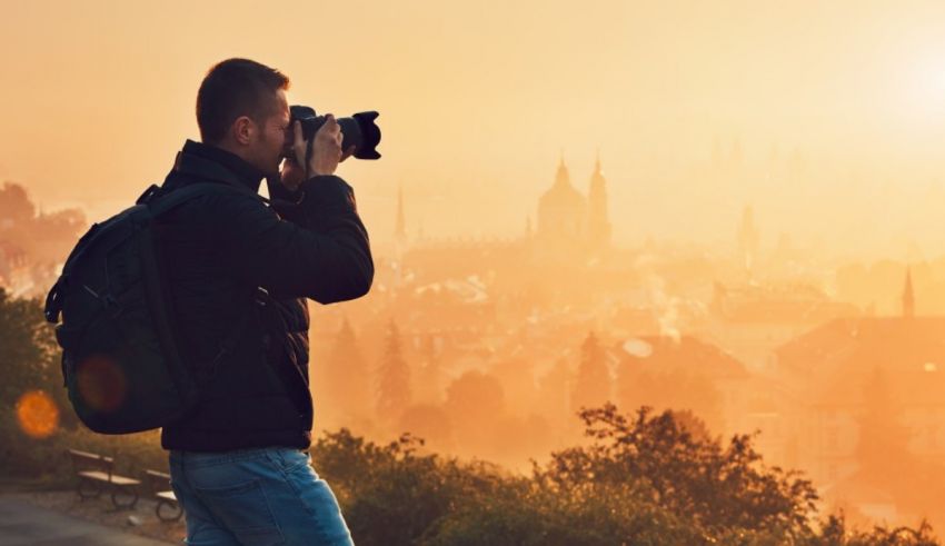 A man is taking a picture of the city at sunset.