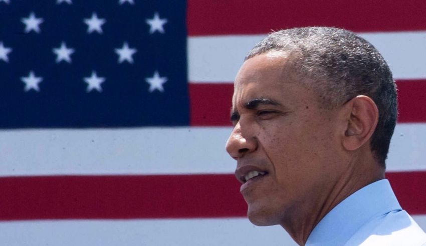 President barack obama stands in front of an american flag.