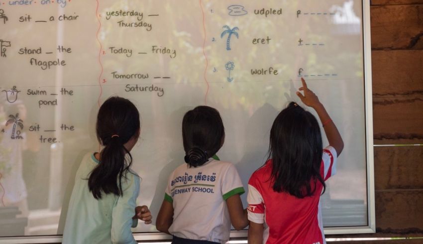 Three young girls standing in front of a white board.