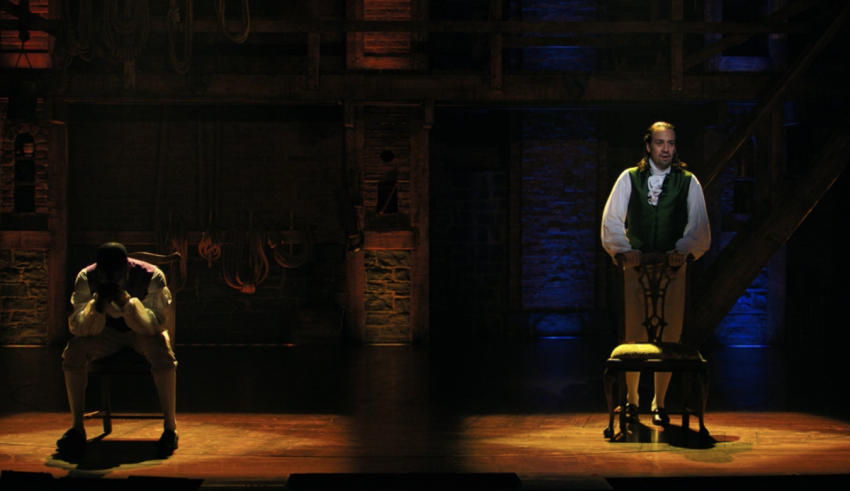 Two men standing on stage in a dark room.