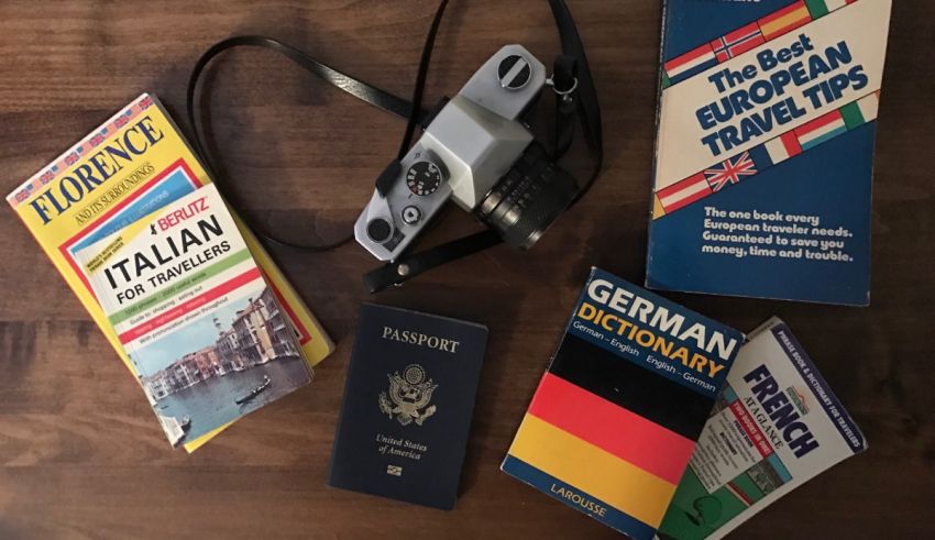 A travel guide, passport, camera, and other items on a table.