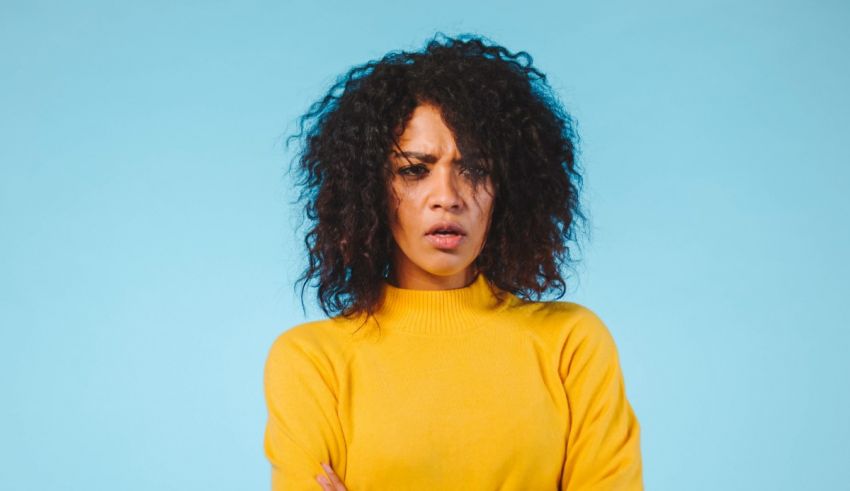 A young woman with curly hair standing in front of a blue background.