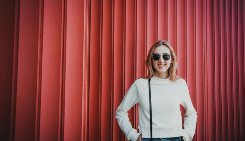 A woman in sunglasses standing in front of a red wall.