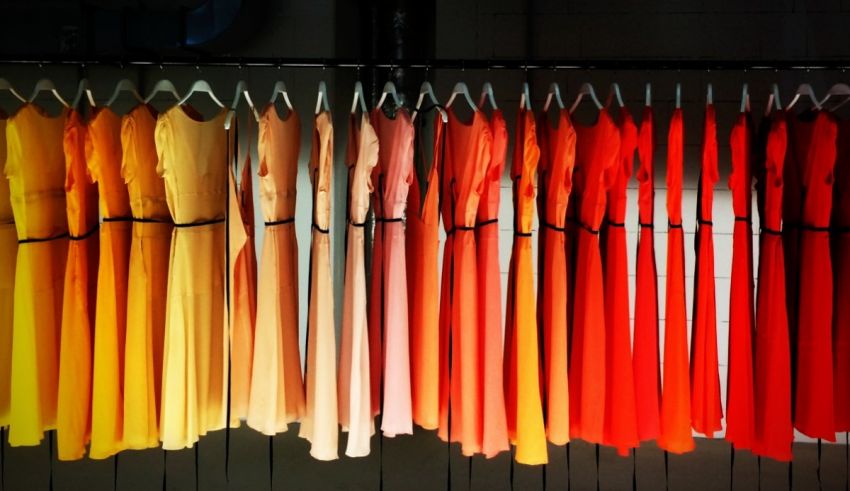 A row of orange and yellow dresses hanging on a rack.